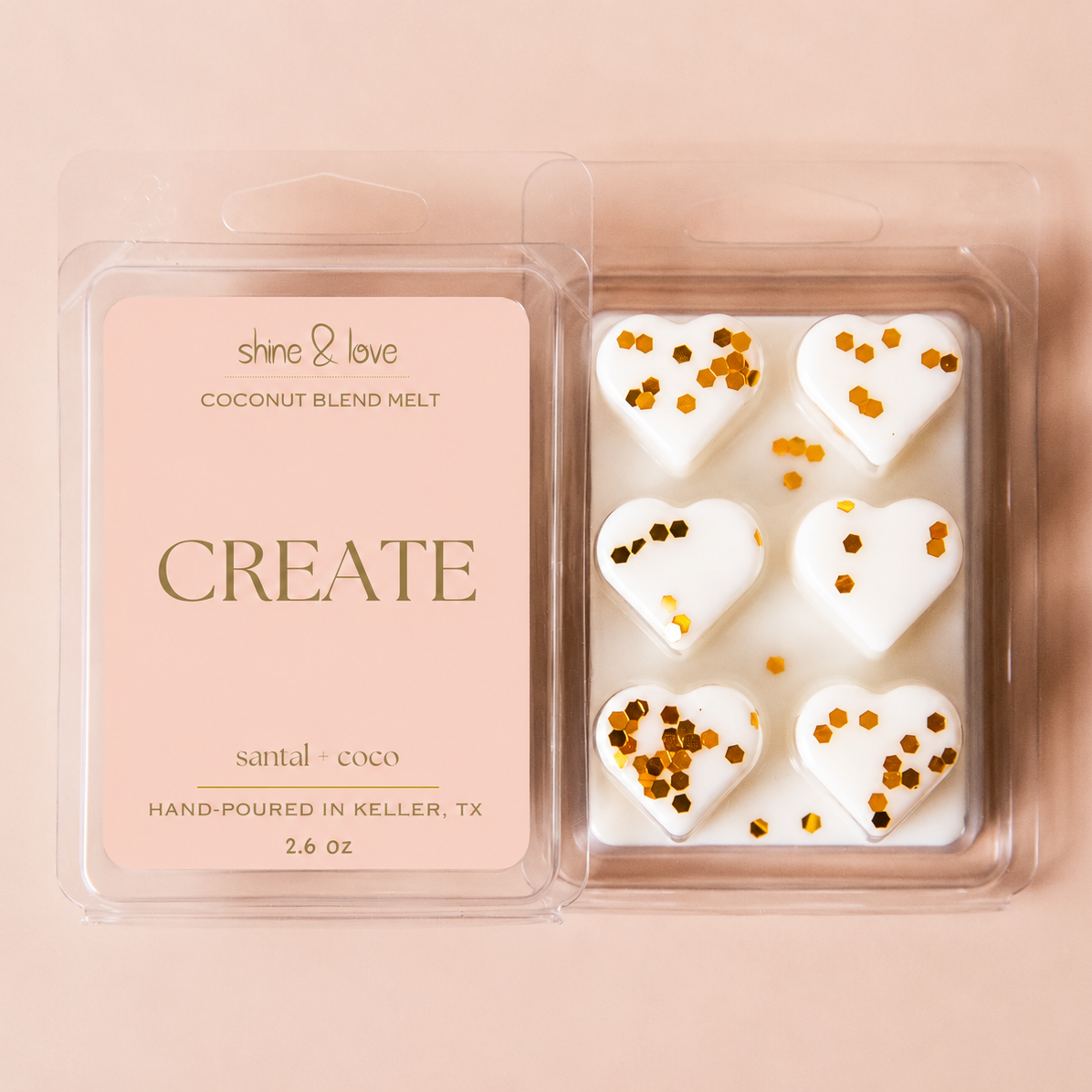 A clear plastic clamshell package of wax melts shown open, with a pale pink label reading 'shine & love coconut blend melt CREATE' and five white heart-shaped wax pieces inside, each topped with scattered gold confetti, on a soft peach-pink background.