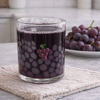 Glass of grape juice with grapes on a kitchen counter