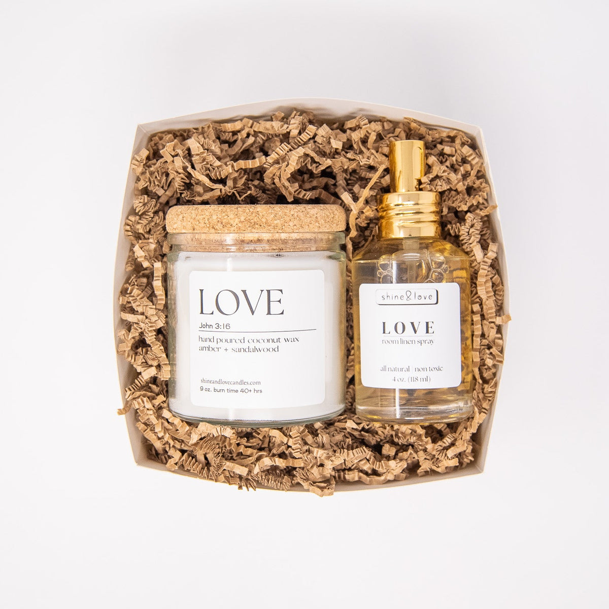 Two products, a candle and a spray bottle, in a decorative box on a white background.