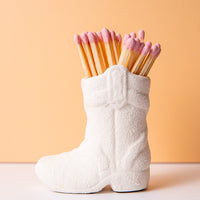 White cowgirl boot filled with pink matches as a gift
