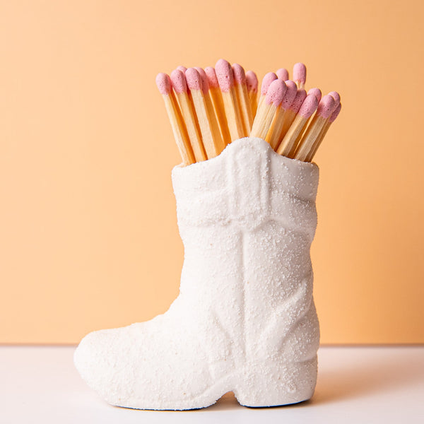 White cowgirl boot filled with pink matches as a gift
